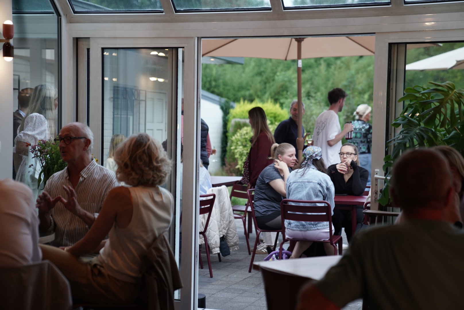 Gasten binnen en op het terras van Monday & Co